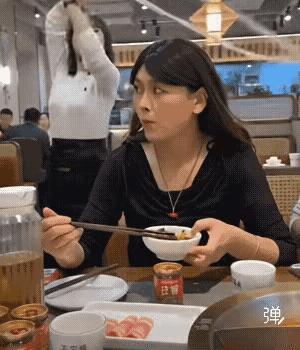 火锅店内，一位时尚女士吃着火锅，旁边的女拉面师傅，展现着自己的拉面才艺，在空中舞