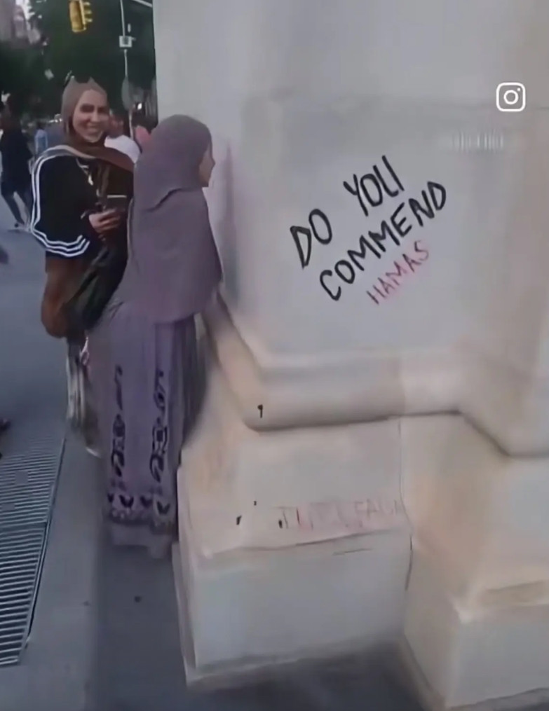 纽约街头的墙上，手写的哈马斯爱心，有伊斯兰女子路过献上祝福。尽管身在异乡，但对