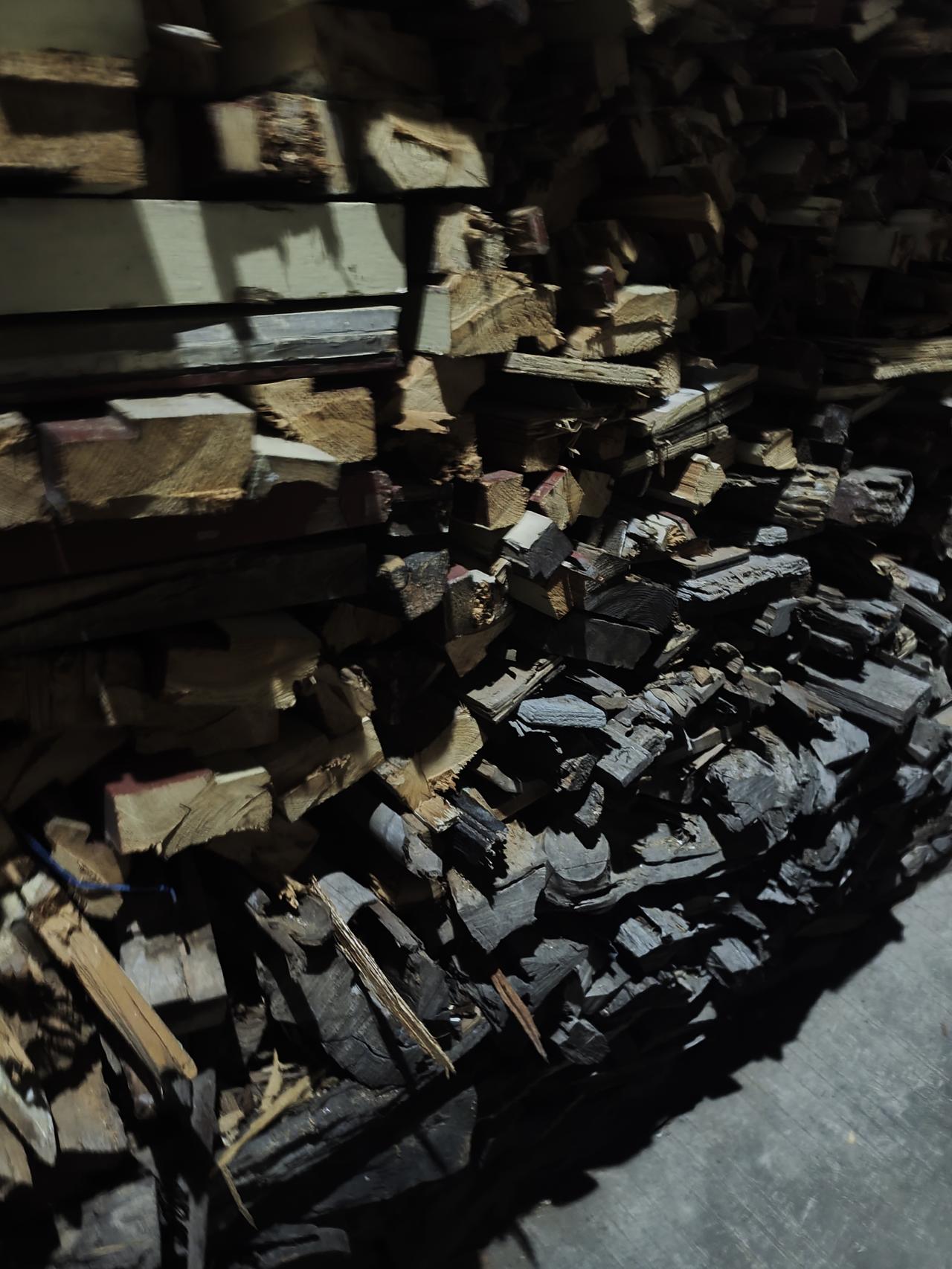 我在一栋房子围墙外，看到堆着很多的木材，在我们这个地方还有很多家都是烧柴火的。