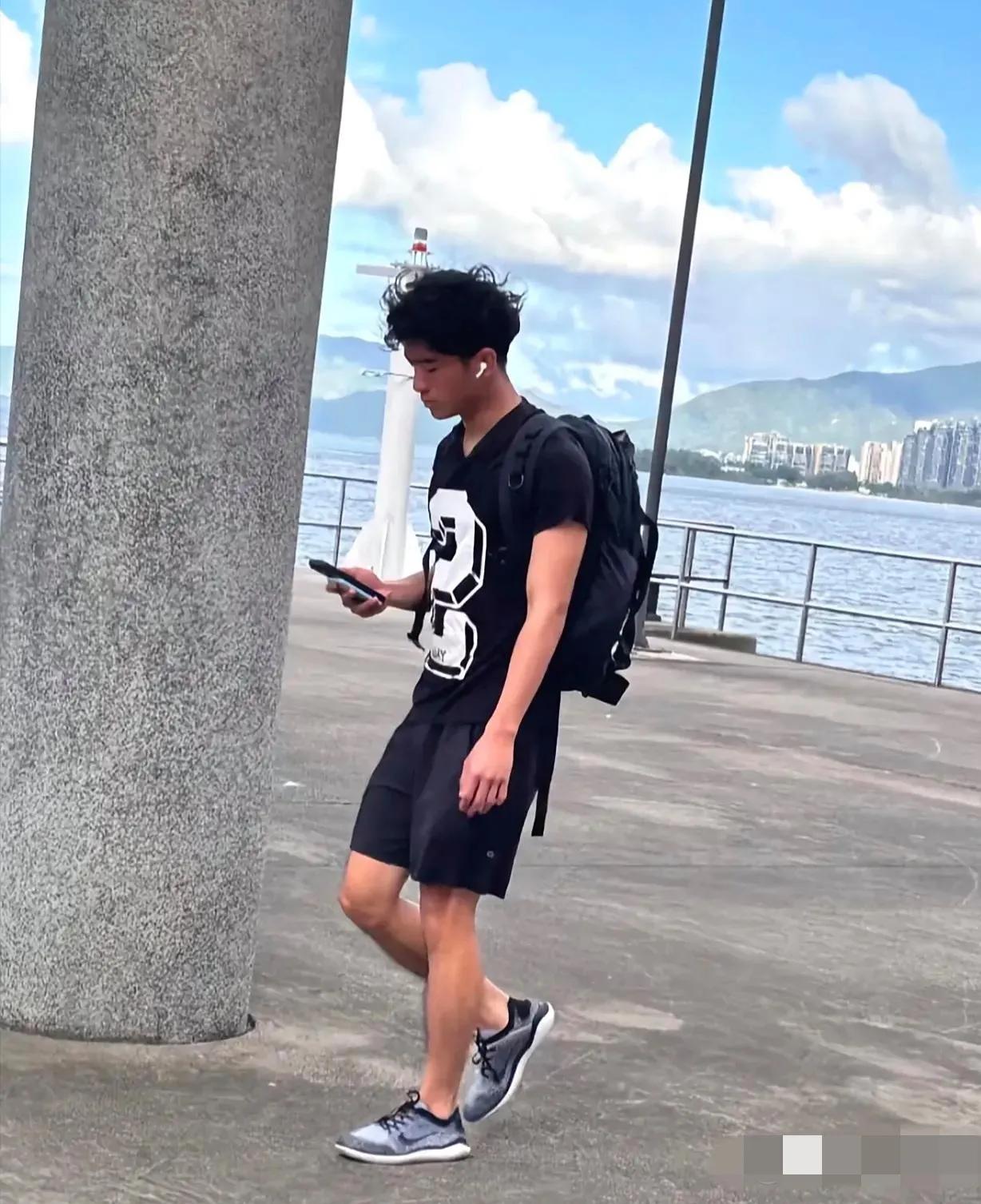 谢霆锋长子谢振轩在香港被拍：皮肤偏黑，卷发轻扬，背包低头，边走边看手机听音乐，身