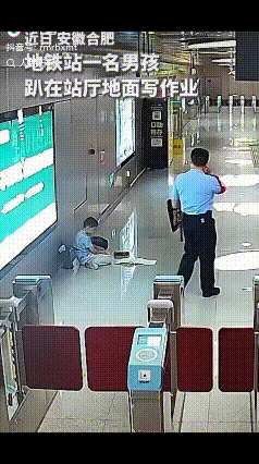“上人民日报了！”合肥地铁站内，一男孩趴在站厅地面上写作业，辅警看见后赶紧喊话让