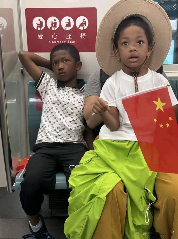 地铁上看到两个黑人小孩坐在椅子上，其中有一个小孩手上还拿着中国国旗？刚开始还以