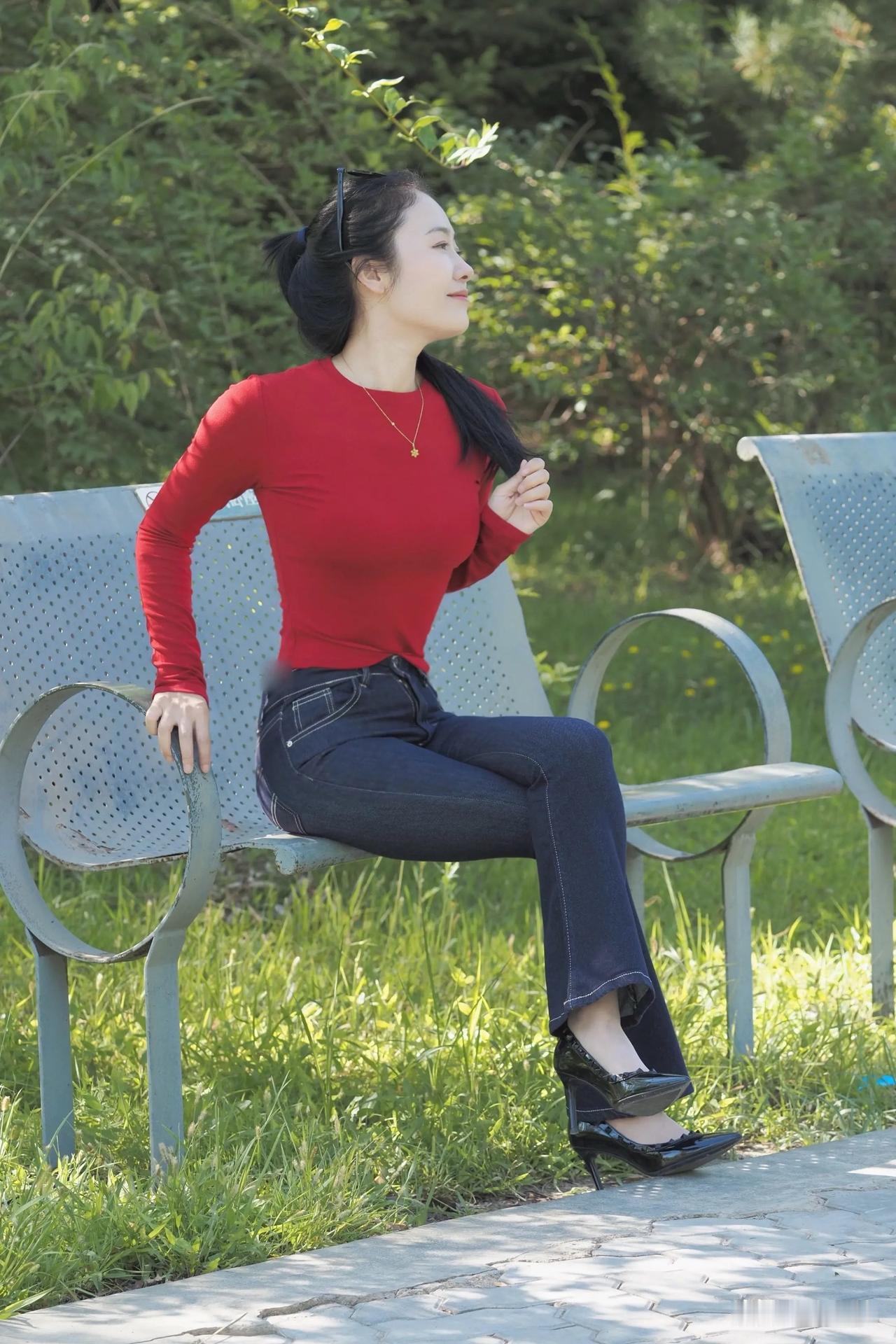 阳光下的红衣少女，静坐长椅，享受宁静时光。