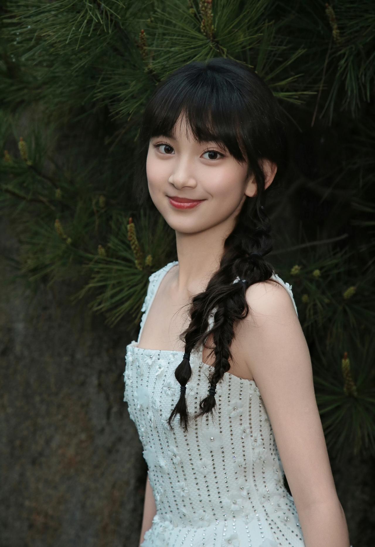 缀着碎钻的白裙闪着微光，麻花辫晃着少女的灵动，像藏在深绿里的小小星辰，带着纯粹的