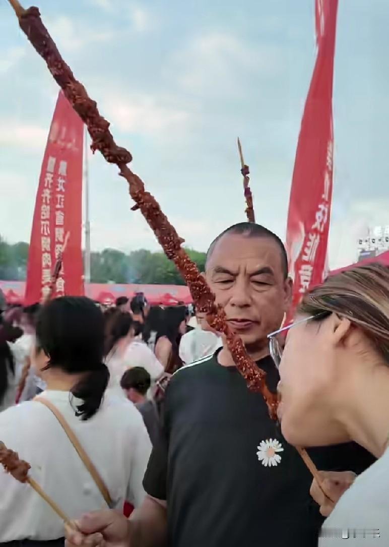7月12日，黑龙江齐齐哈尔烤肉节人山人海，原地开烤，人手一串“大宝剑”，一米长的