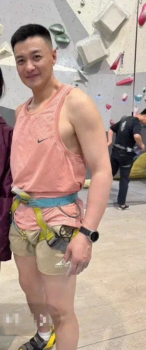 44岁周一围攀岩被偶遇，周一围穿着一件粉色运动背心，搭配卡其色短裤和专业的攀岩安