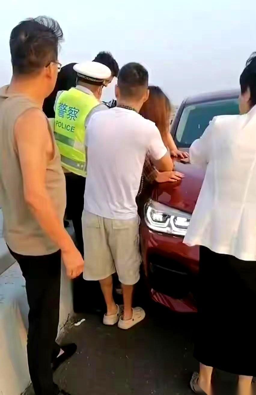 脚底下就是翻滚的海水，胶州湾大桥的风吹得人站都站不稳。那个女人翻过护栏坐在外侧