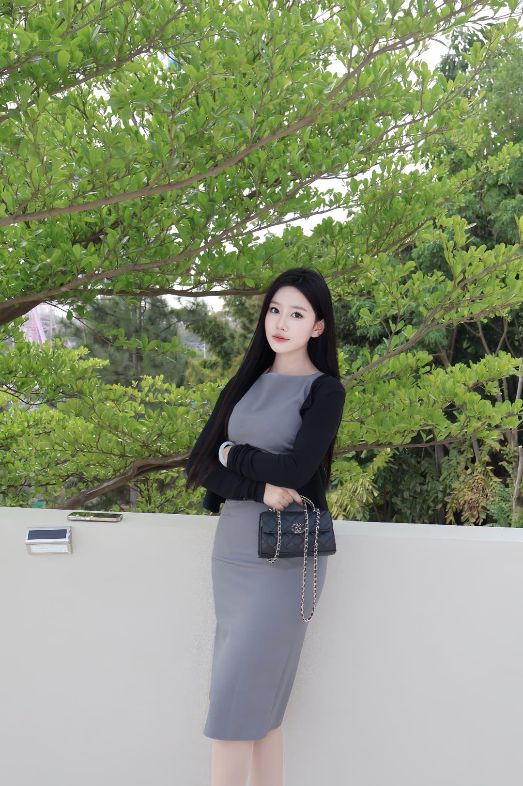 灰色收腰包臀连衣裙外搭黑色短款开衫，脚穿黑色高跟鞋，精致又得体，展现出知性的美。
