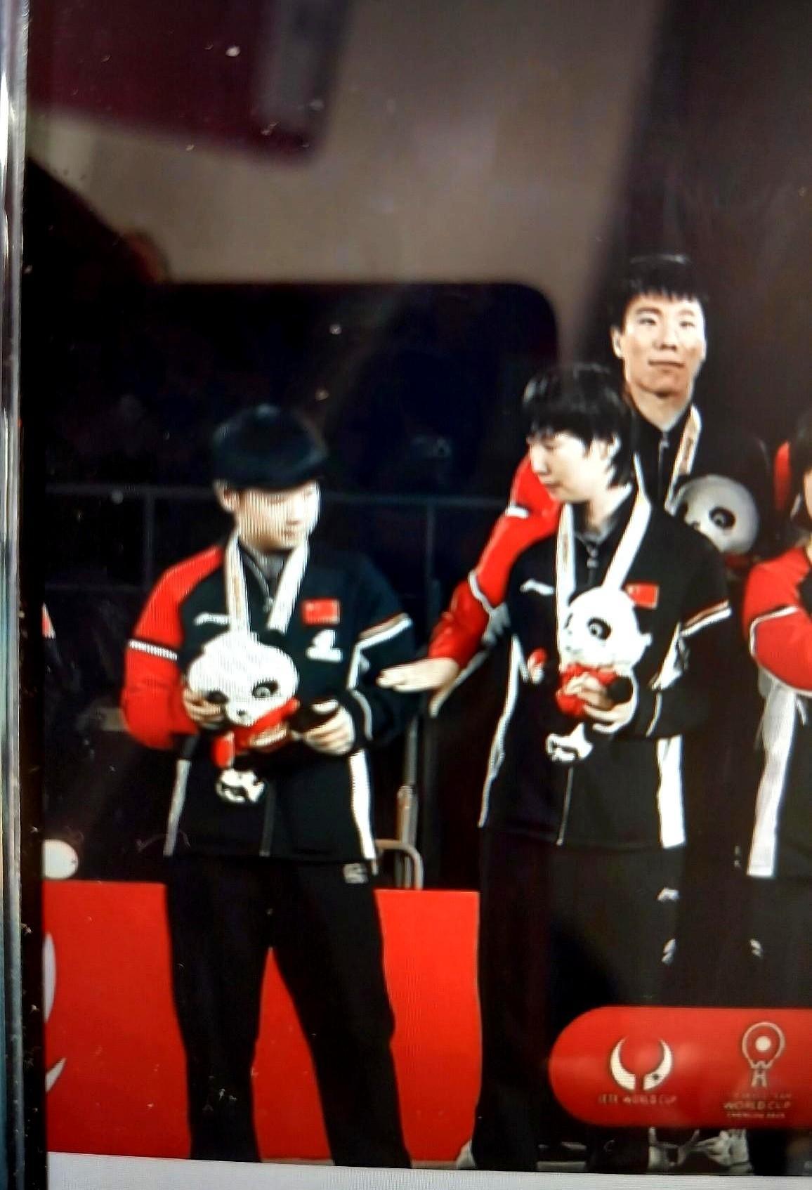 孙颖莎站在领奖台咬着下唇憋泪时，王曼昱的手掌轻轻拍在她胳膊上——这1秒的触碰，比