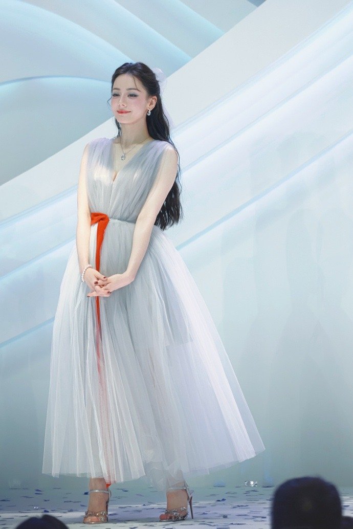 在光影交织的红毯上，迪丽热巴身着浅蓝色轻纱长裙款款而来。轻盈的薄纱随风轻拂，衬