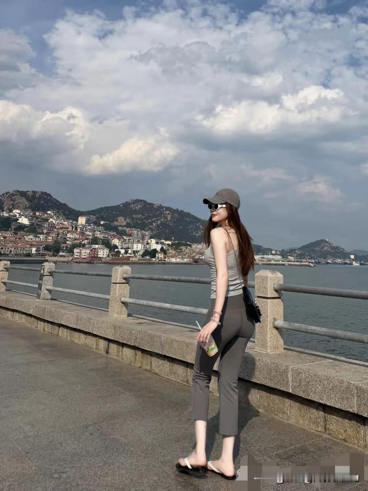 这是在青岛还是大连呢？桥上美女，修长臂，腿长，戴墨镜，提奶茶，遮阳帽走起，发长而
