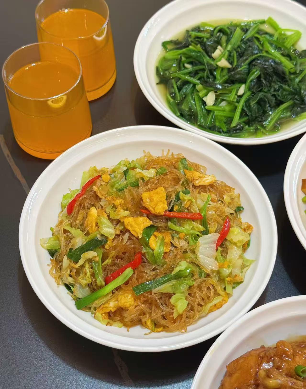 一顿丰盛的饭菜，有炒面、青菜和汤。