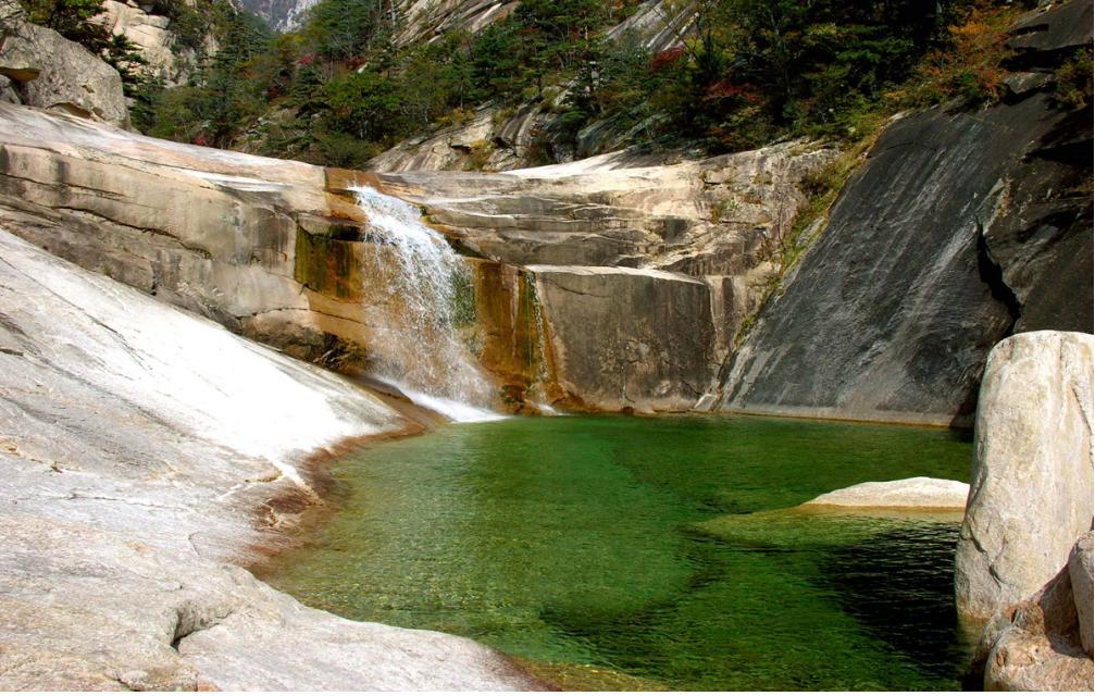 金刚山的溪谷和水潭朝鲜名山金刚山有巨大的层岩绝壁、千沟万壑、大小水潭，与绿树相