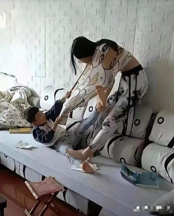 沙发上那小男孩，使劲拽妈妈衣服，都快给扯烂了。妈妈呢，一只手抓着他的脚，另一只脚