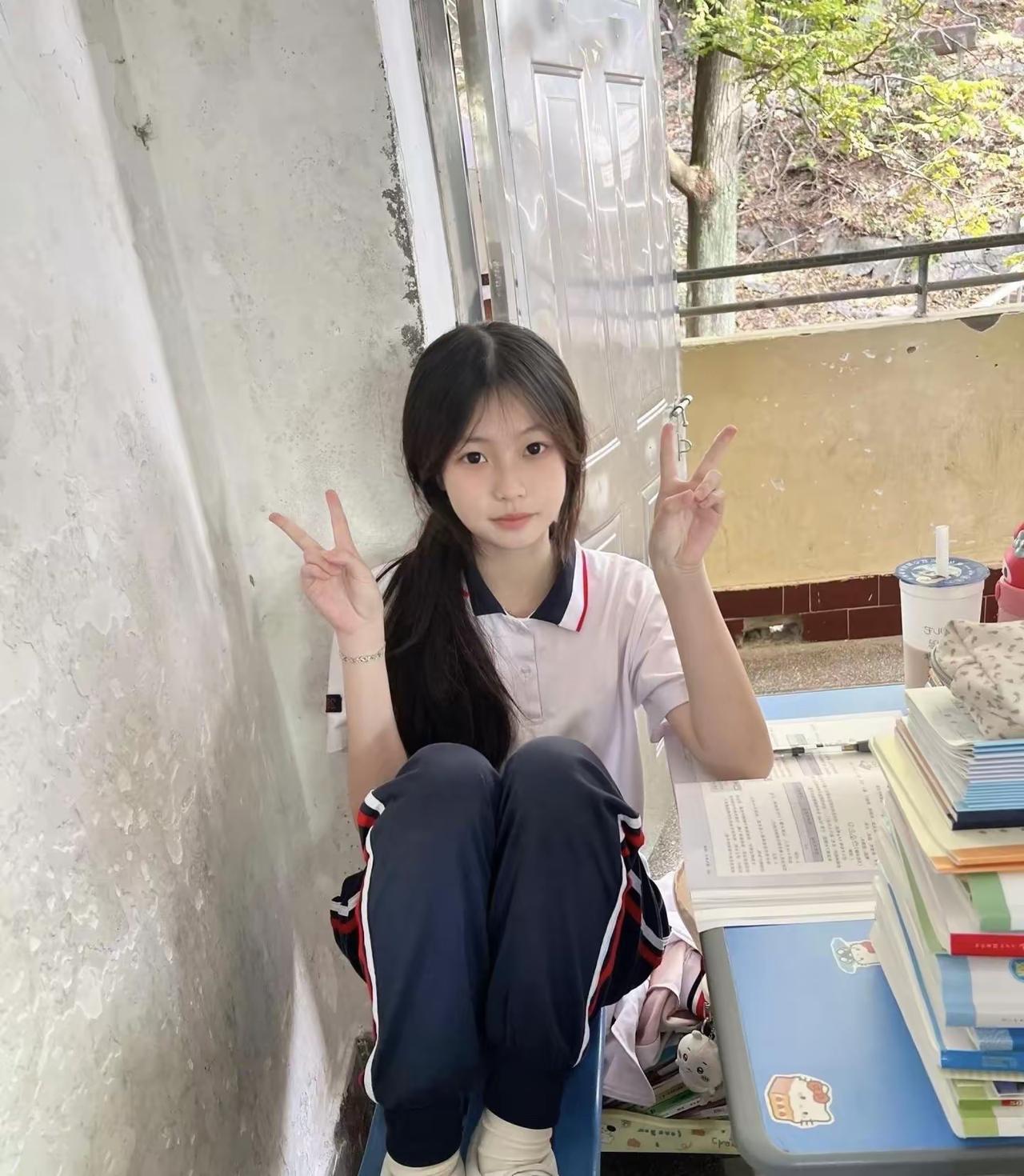 她坐在墙边，双手比着“V”字手势。甜系手势写真脸颊比心比心