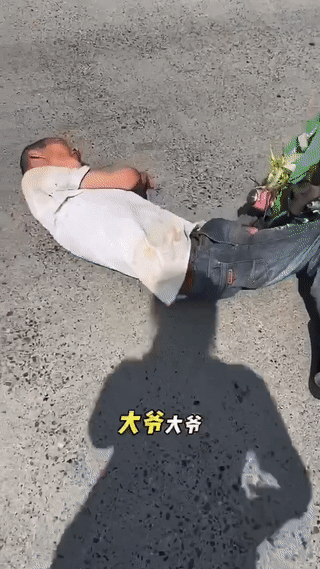 四川，一位老人不小心从自行车上摔了下来，就那么直直地躺在了马路中间。可没一辆车敢