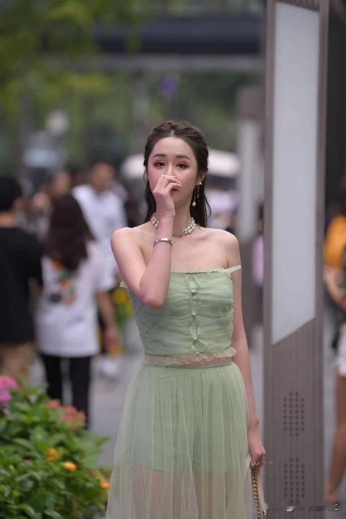 一个穿着绿色裙子的女生在街上。