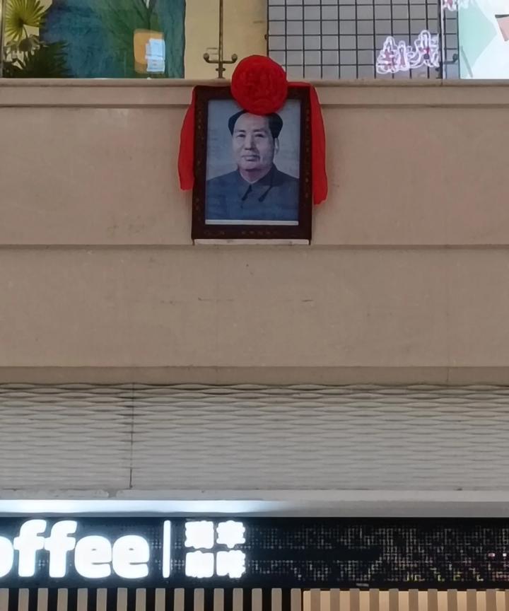 商场大厅正面的墙上，挂着一幅伟人的画像，这幅画像已经挂了许多年了。这家商场生意