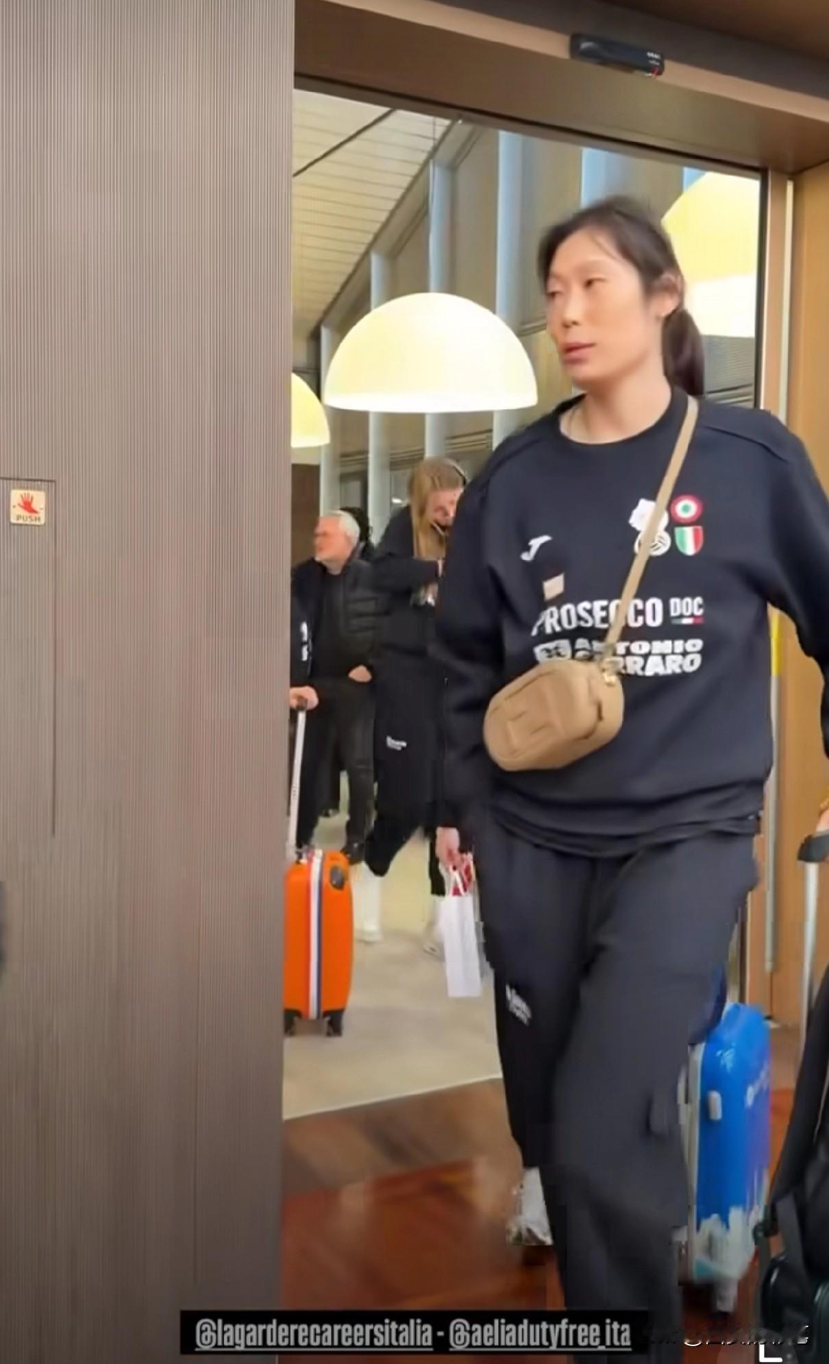 朱婷出征巴西世俱杯的新照来了[呲牙笑]瞧，朱婷身穿蓝色队服，斜挎驼色小提包，尽显