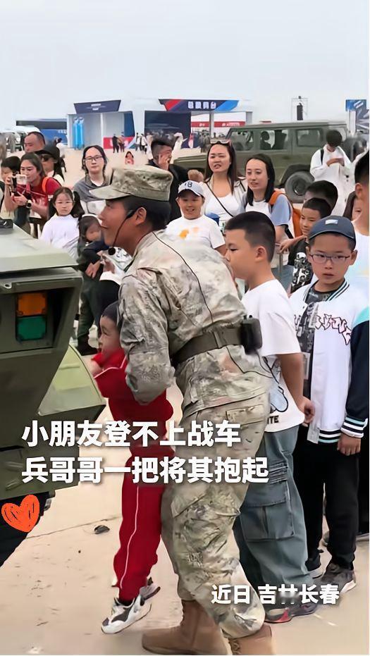 吉林这兵哥哥一伸手，全网都被暖到了！长春航展上，穿中国红的小男孩踮脚够坦克轮