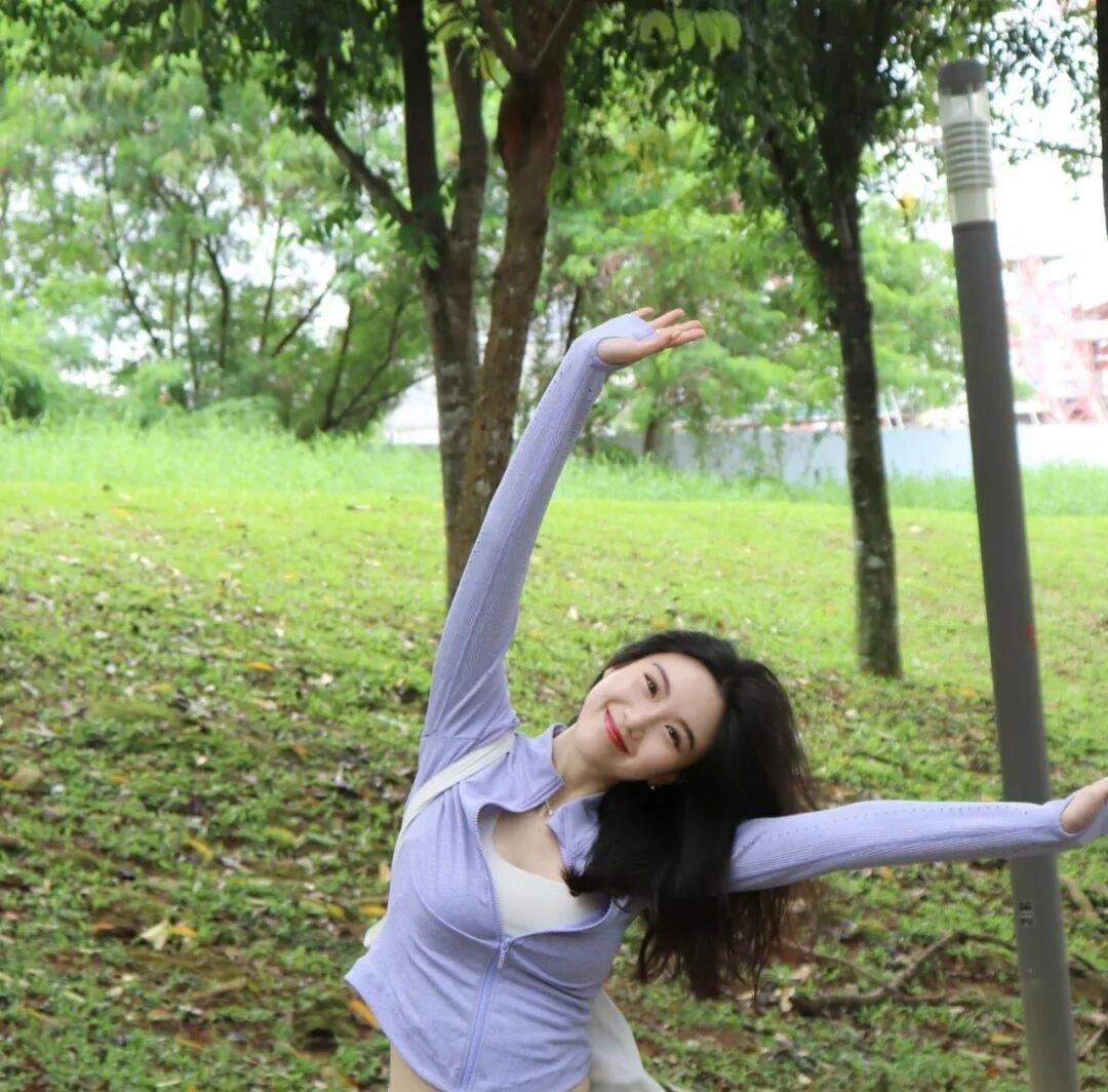 笑容超甜美的女孩，一身运动休闲穿搭，在公园开心地伸展双臂，迎接大自然的怀抱公园时