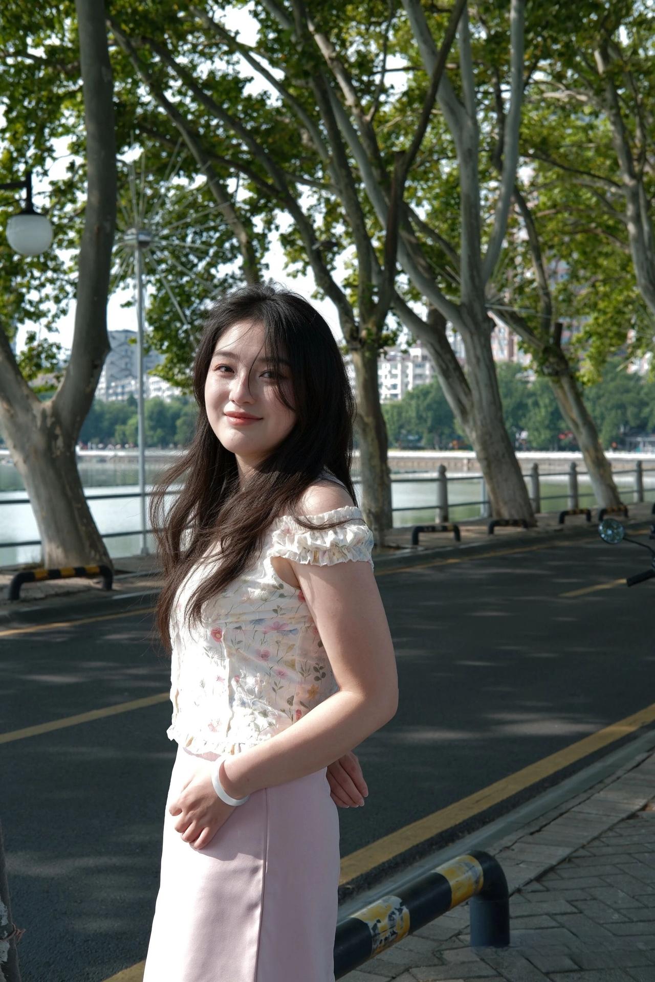 阳光下的少女，笑靥如花，漫步在绿树成荫的河畔。