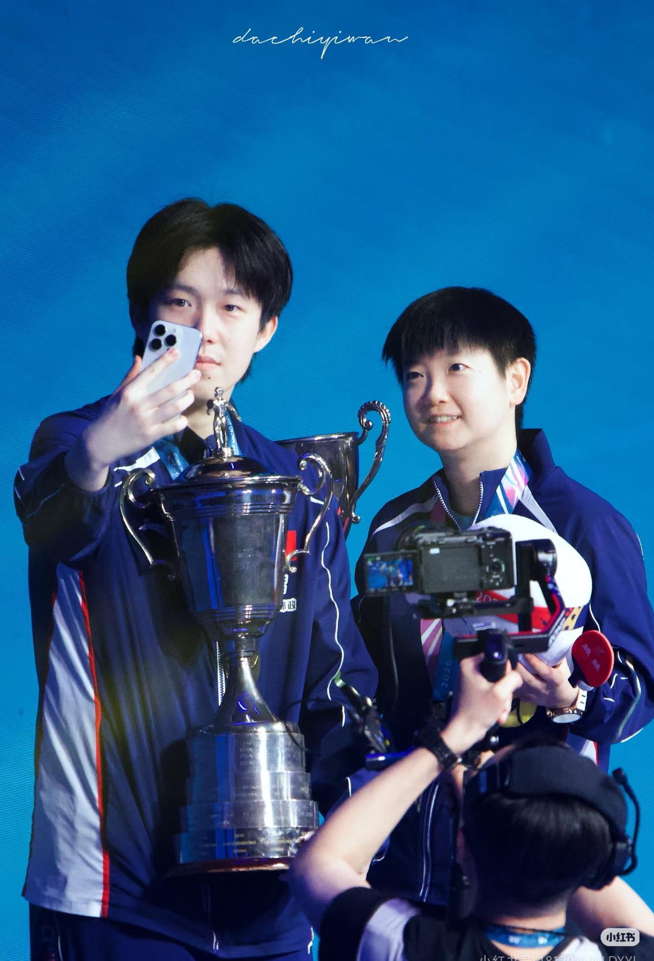 孙颖莎凌晨4点拖着箱子，箱子外挂着一条没拆吊牌的粉色新裤子。网友看到照片，说