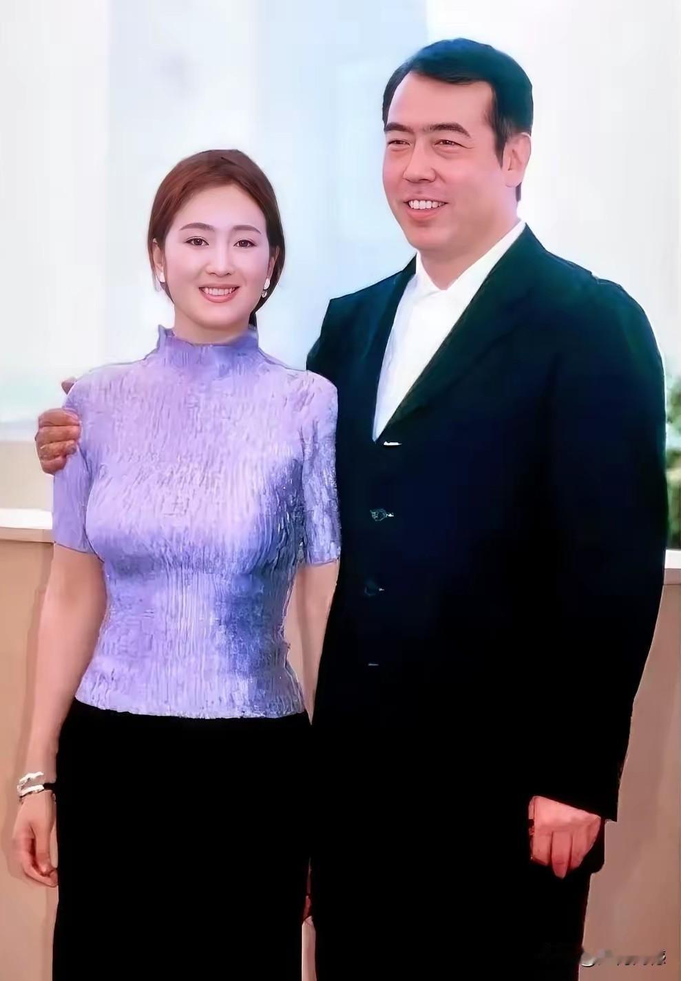 巩俐和这个男人拍摄的这张合影照片，拍摄的效果是特别喜庆的，两个人站在一起，从从容
