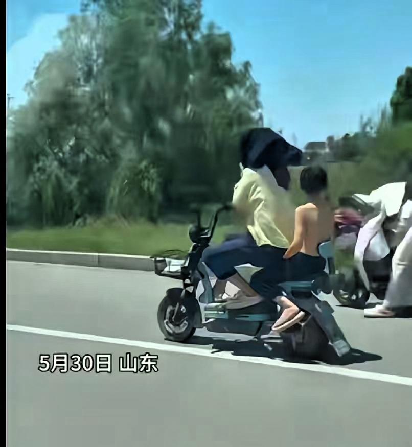 绝对亲生的！5月30日，山东，妈妈骑着电动车带着儿子，因为太阳大，妈妈怕晒，情