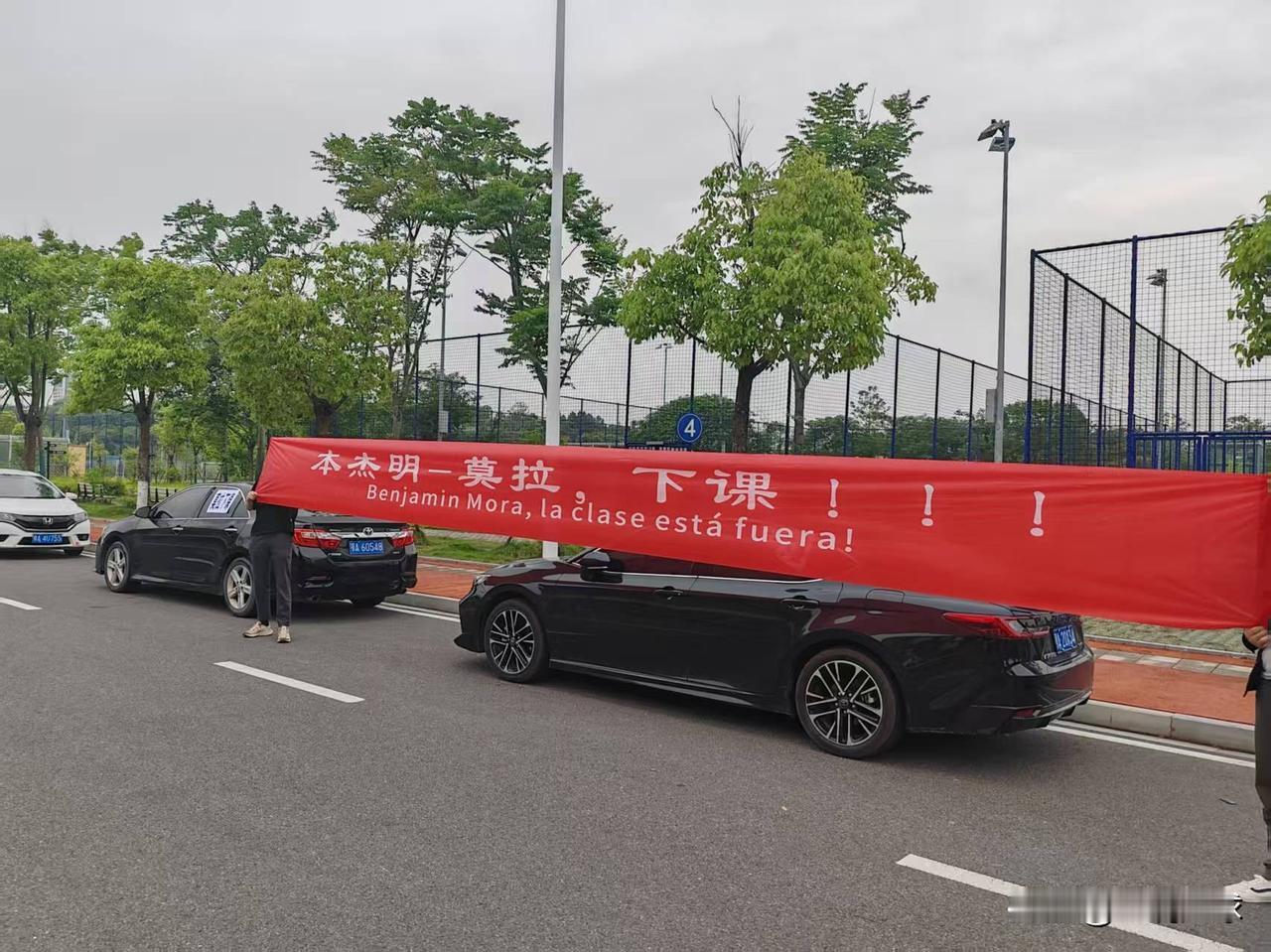 此时此刻的武汉三镇训练基地门外，武汉球迷在基地外面拉起了“莫拉，下课”的横幅……