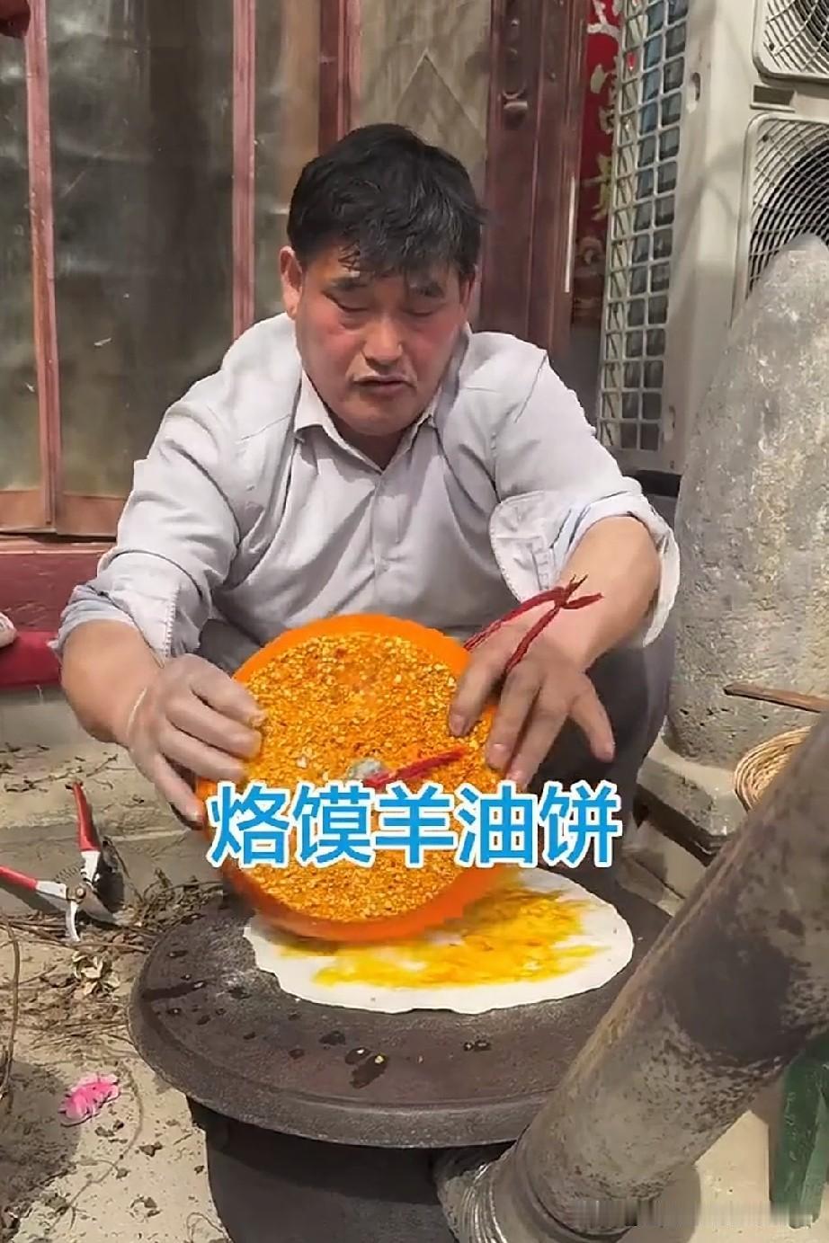 大衣哥在家烙烙馍，这或许是当地的吃法。他在烙锅上放一张面饼，接着拿一大块羊油辣子