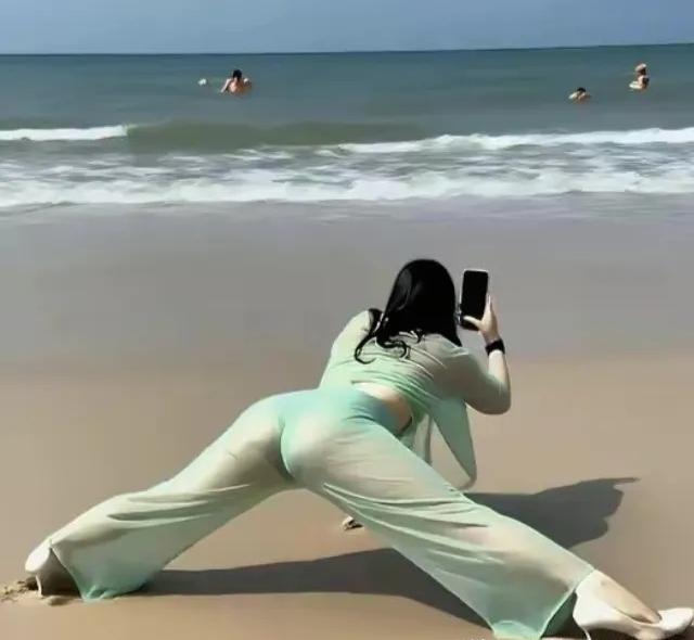 别人在海边凹造型，美女摄影师却在海边“凹”镜头，顺便把自己也美成了一幅画。她