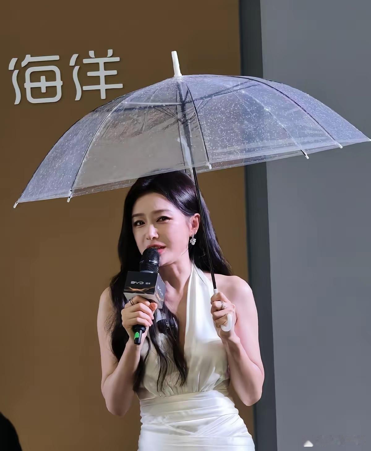 47岁？说她30岁我都信！杭州活动上，秦岚一身白色深V长裙，撑着透明雨伞，长发飘
