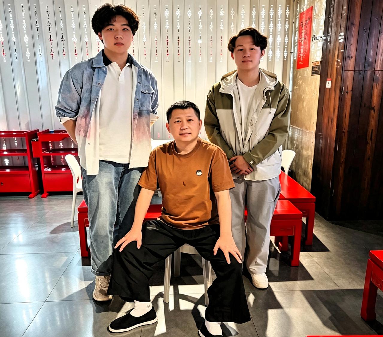 何沄伟带着俩小年轻合了个影。看这架势，应该是他收的徒弟。娃娃们看着还一脸稚气，但