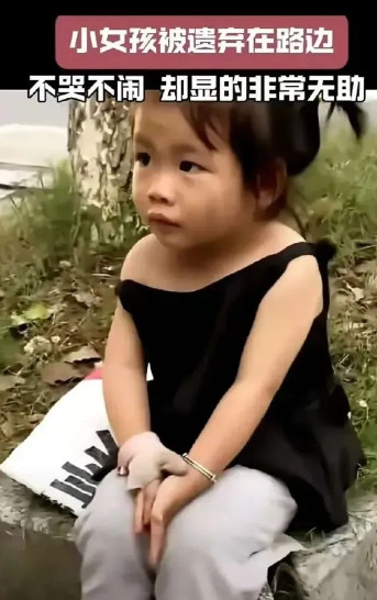 泪目了，被遗弃在路边的小女孩。一女孩不知何故被遗弃在马路边，女孩不哭不闹，浑身脏