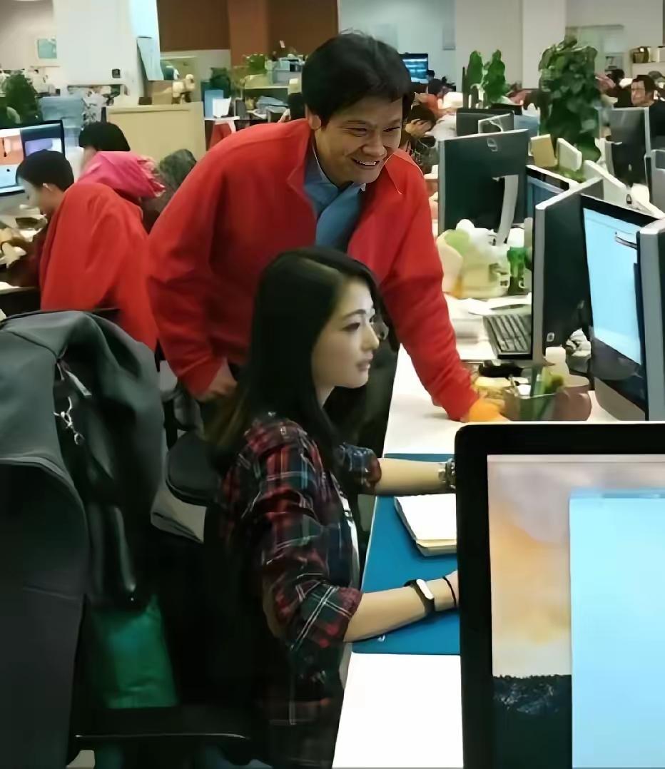 2014年小米初创期，雷军俯身视察，美女工程师张功埋头工作的留影。镜头下雷军身着