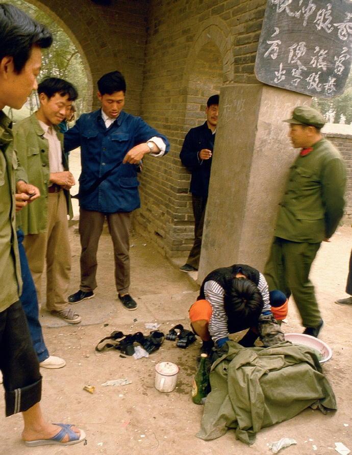 1984年，洛阳白马寺里，一名男子蹲在地上，双手戴着皮手套，用一块布盖在脸盆上。