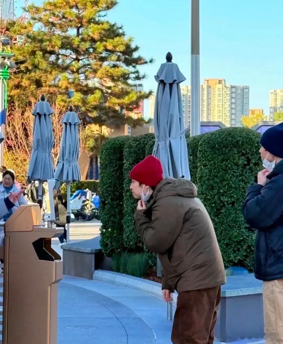 董子健带着女儿现身北京环球影城，戴着红色帽子，穿着棉服，侧颜看着肤色很白，鼻梁特