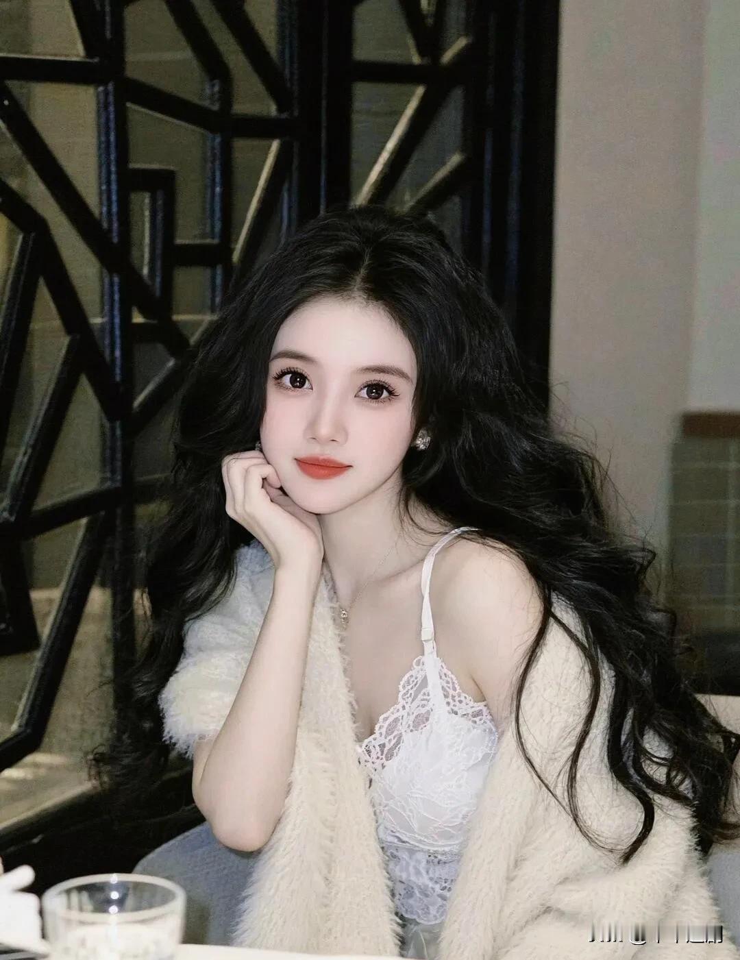 毛绒披肩裹着蕾丝吊带的柔，黑卷发垂落时漫着轻甜的靡。唇上暖调红衬得眼波更软，抬手