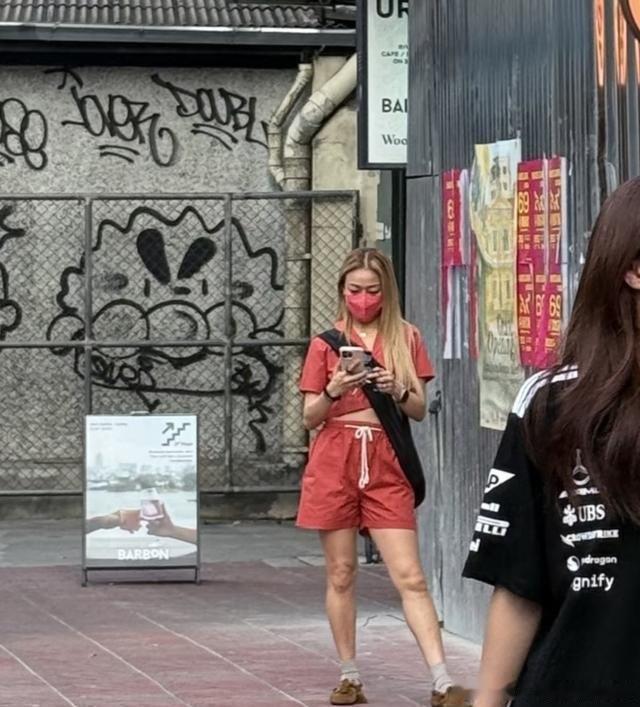 45岁容祖儿穿红色露脐装现身泰国，身边短发女士不是李璇，团队沉默不回应，网友问：