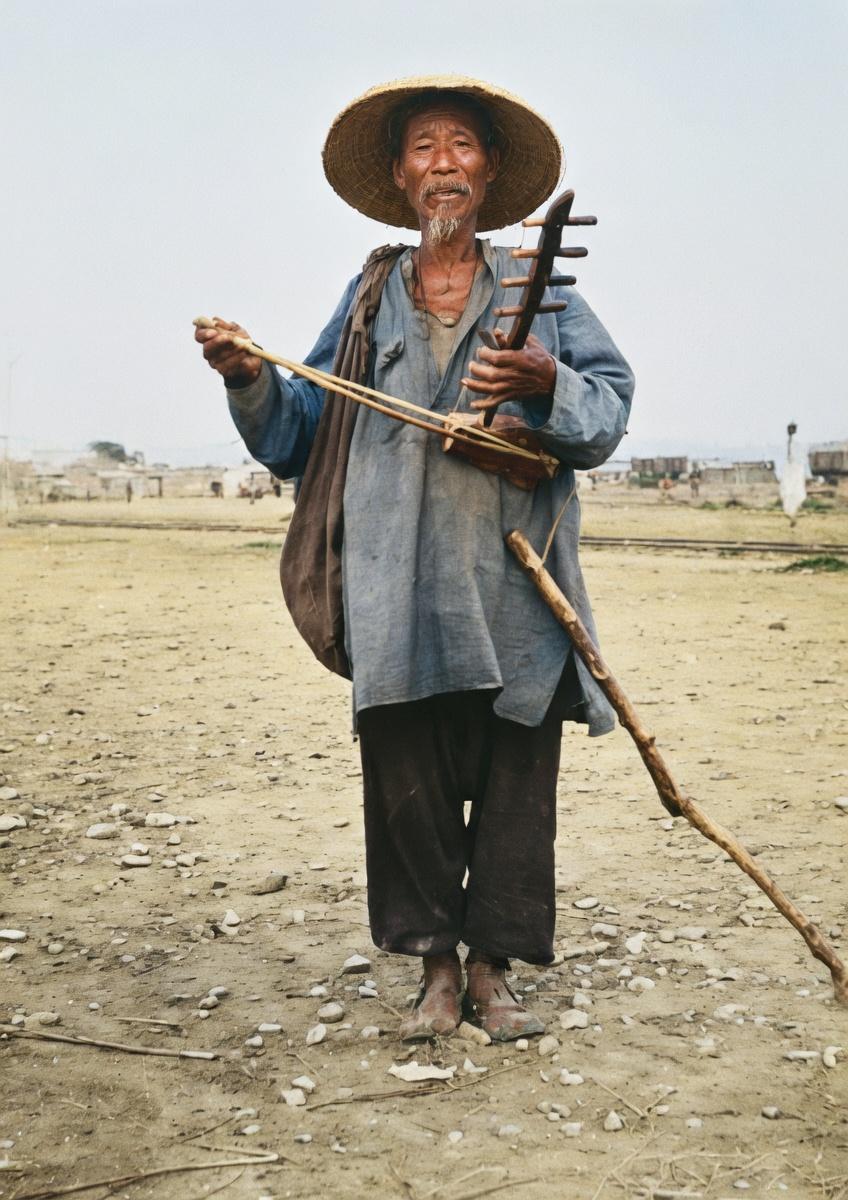 清末至民国初年，一位赤贫的民间艺人在街头卖艺乞讨的瞬间这是一位年事已高的老年男