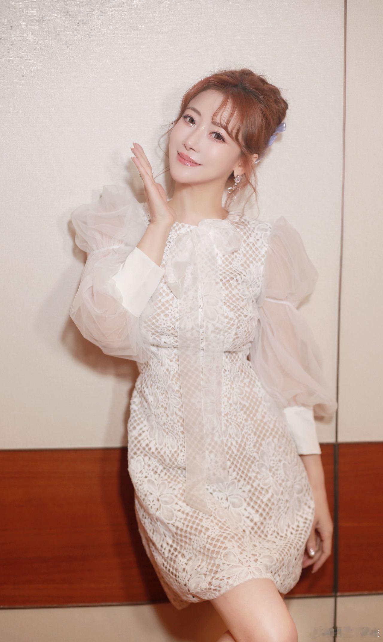 姐姐这是吃了什么“冻龄糖果”呀！一袭白色蕾丝裙+泡泡袖，甜到冒泡，镂空细节又带点