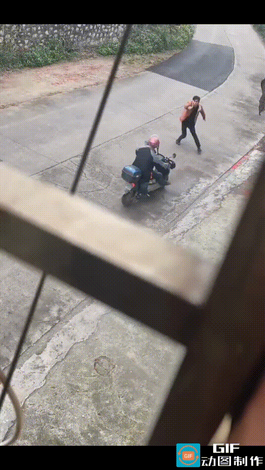 一名男子站在马路上，摆出怪异的姿势，挡住迎面驶来的一辆电动车。电动车刚刚停下来