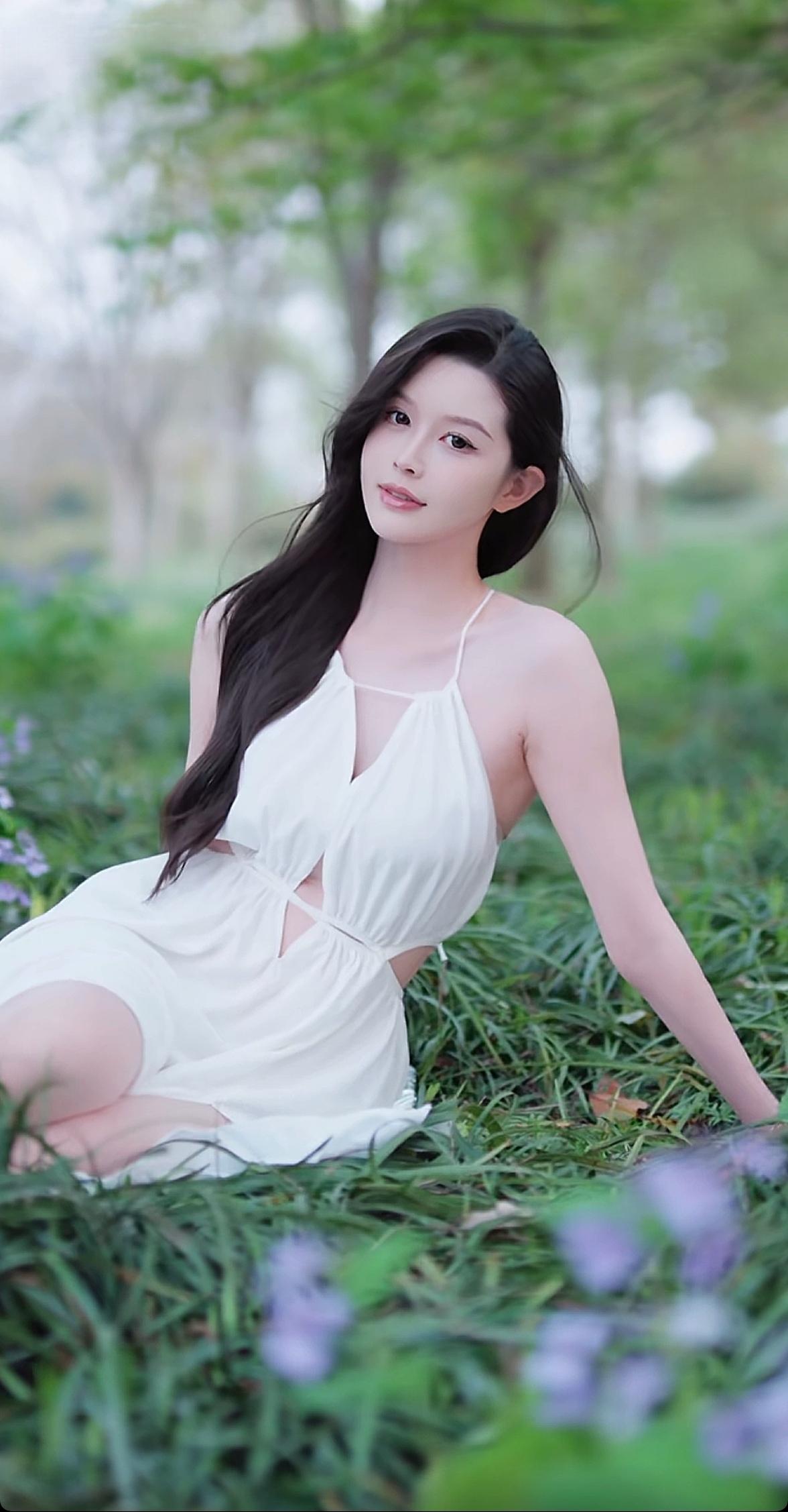 在绿意盎然的公园里，她穿着白色连衣裙，温柔地躺在草地上，仿佛一幅浪漫的画卷。