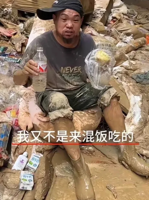 贵州榕江洪灾，他坐在泥堆里，啃着馒头，喝着矿泉水！当有人问“为什么不去领盒饭？”
