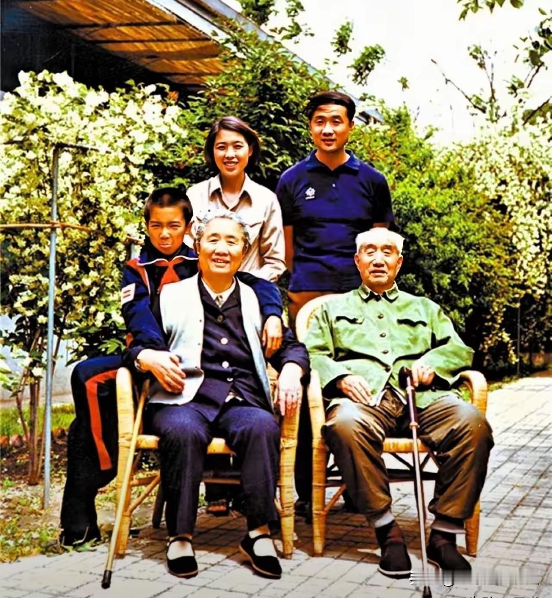 这是开国元帅徐向前的珍贵全家福。庭院繁花掩映，徐向前身着绿色旧军装、拄拐端坐，