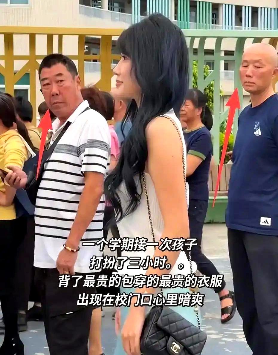 校门口这一幕，把“用力过猛”演明白了。一位来接娃的妈，白背心+缎面裙+名包，镜