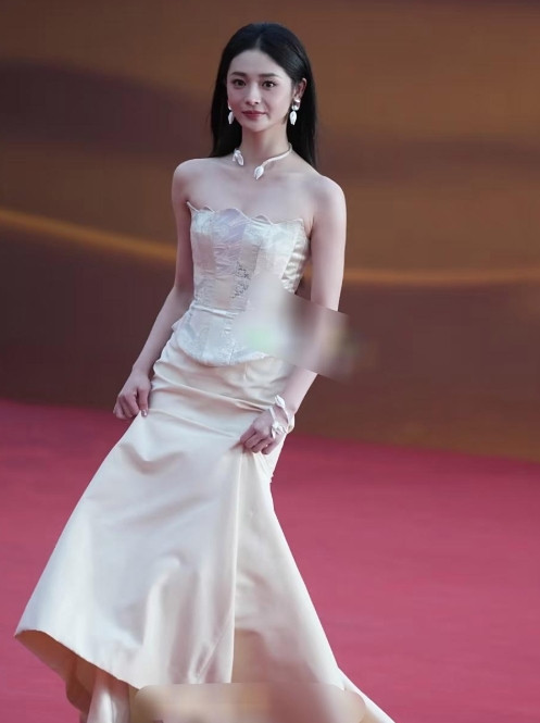 身着优雅米色抹胸长裙的周洁琼立于红毯之上，尽显端庄美丽。