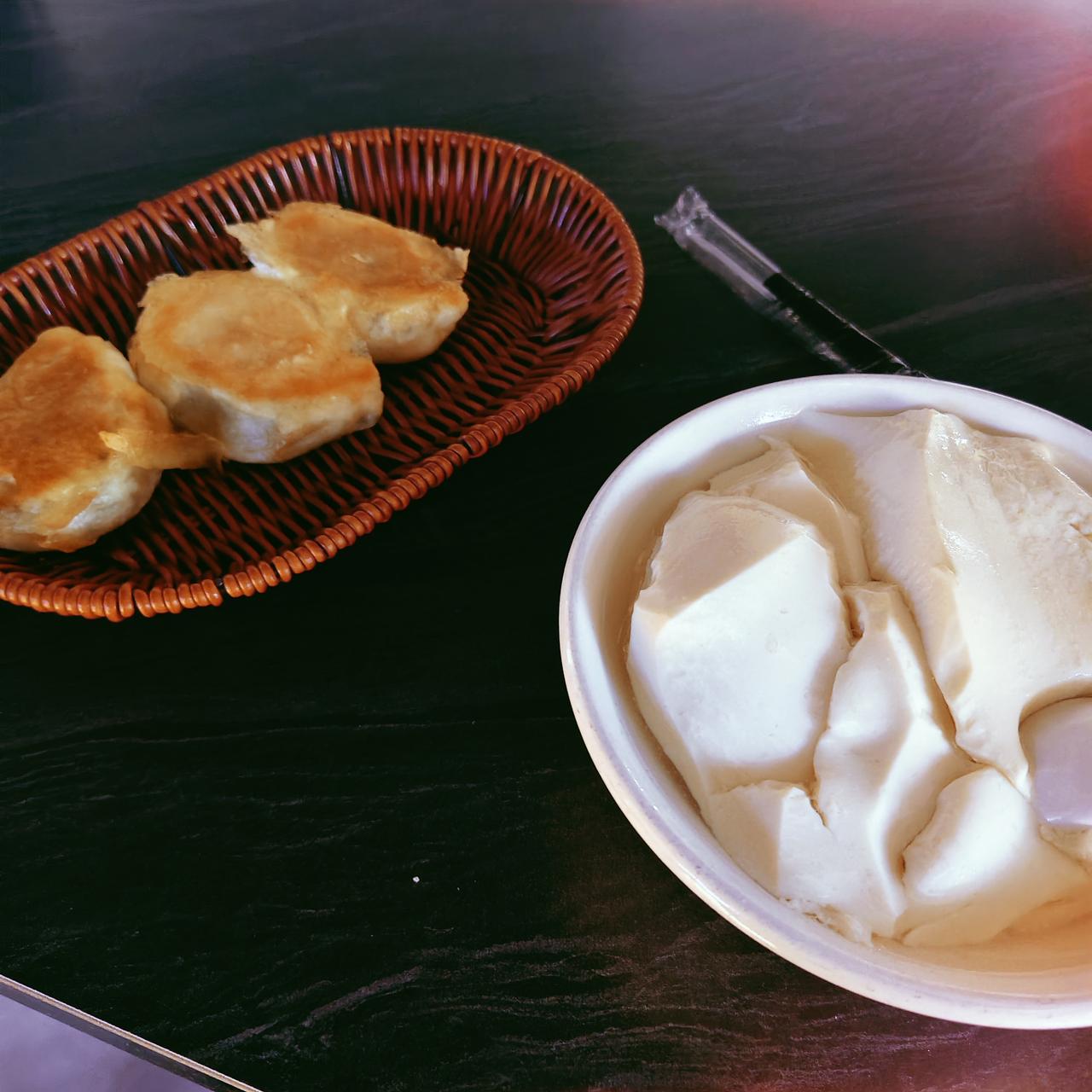 今日早餐，是豆腐脑和三个煎包。在我们这儿，白白的那碗就是豆腐脑，辣的则是胡辣汤。