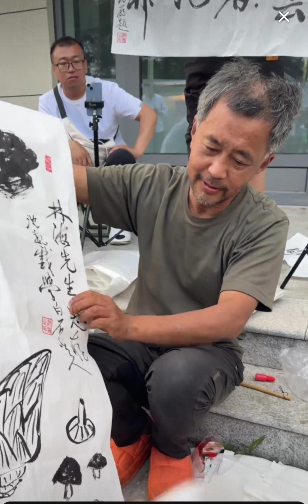 这是近期流浪大师沈巍作画的场景。最近很多人向“流浪大师”沈巍求书画，希望能获得